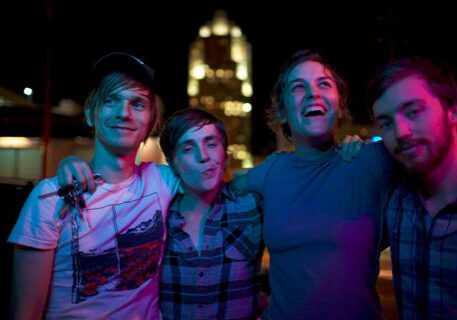 Group of friends smiling under colorful lights.