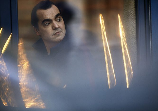 Man looking out window with blurred reflections.