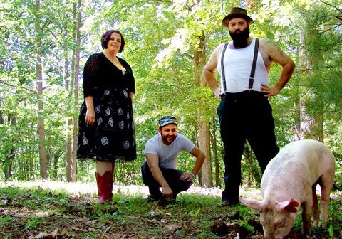 Three people outdoors with a pig.
