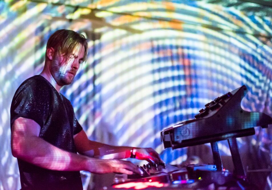Musician playing keyboard with colorful light projections.