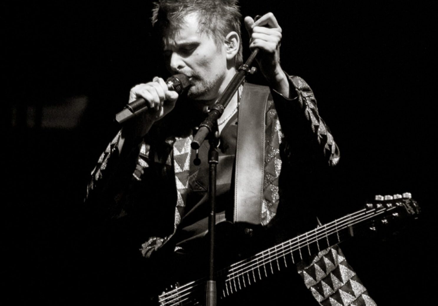Singer performing with guitar on stage.