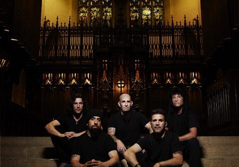 Band sitting on church steps, stained glass backdrop.