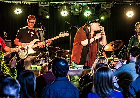 Band performing live on stage with audience.