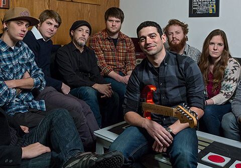 Group of people sitting with a guitar.