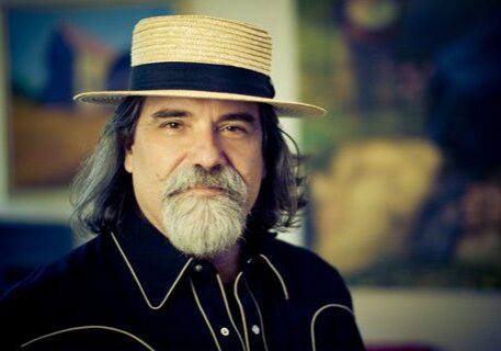 Man with hat and beard, wearing dark shirt.
