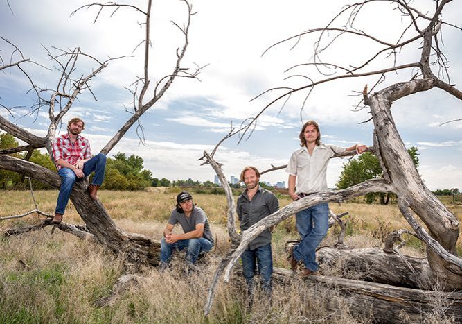 Four men posing on a fallen tree.