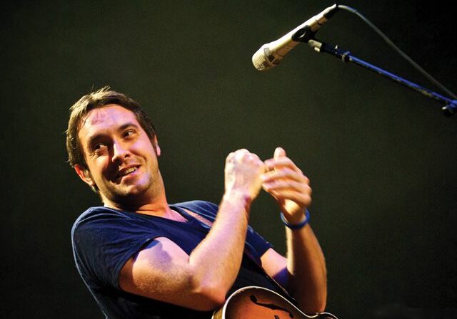 Singer performing with a microphone on stage.