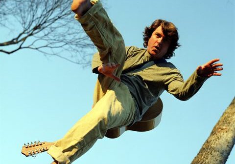 Person jumping with guitar in mid-air.