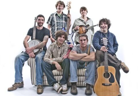 Band members with instruments on a couch.