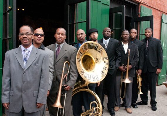 Brass band posing outside with instruments.