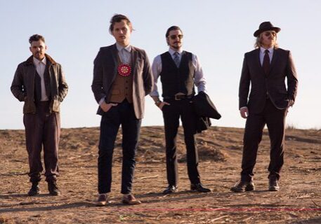 Four men in stylish, vintage-inspired outfits.