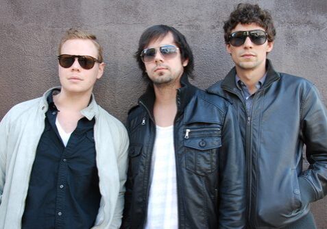 Three men wearing sunglasses and leather jackets.