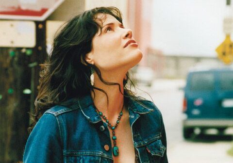 Woman in denim looking up outdoors.