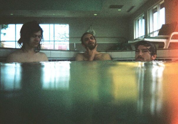 Three people in an indoor swimming pool.