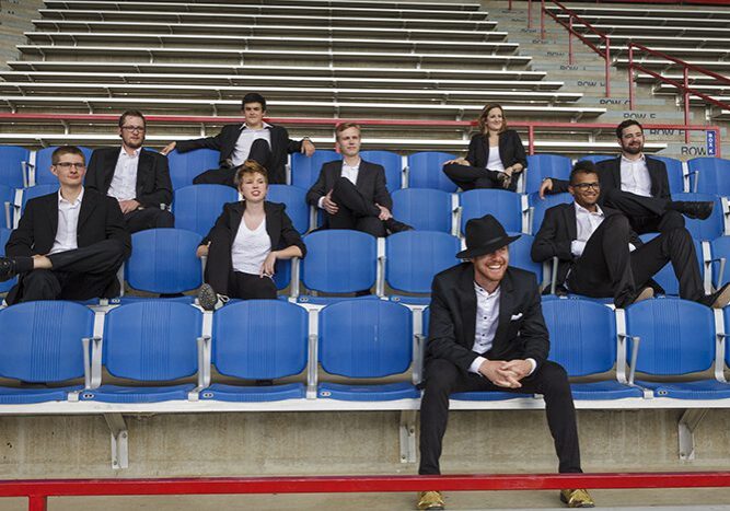 Group in suits sitting on stadium seats.