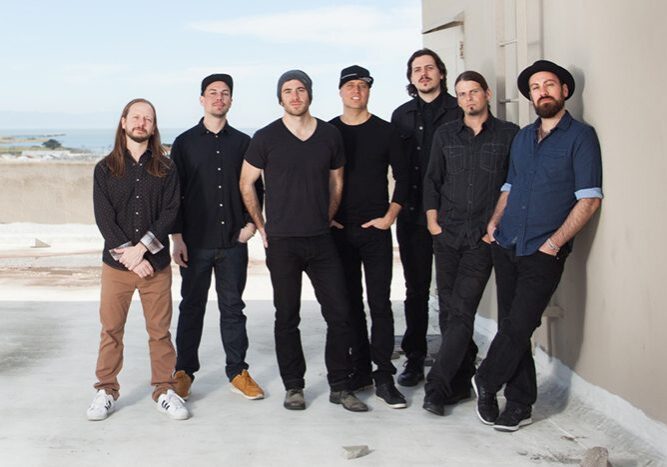 Seven men standing on a rooftop together.