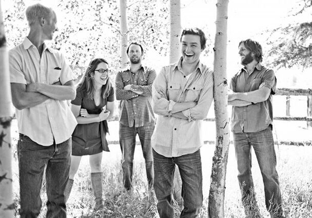 Group of five people smiling outdoors.