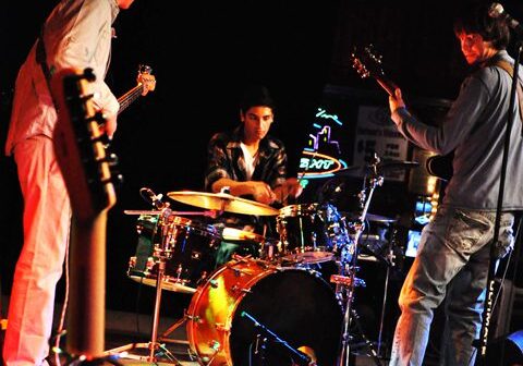 Band performing live on stage with instruments.