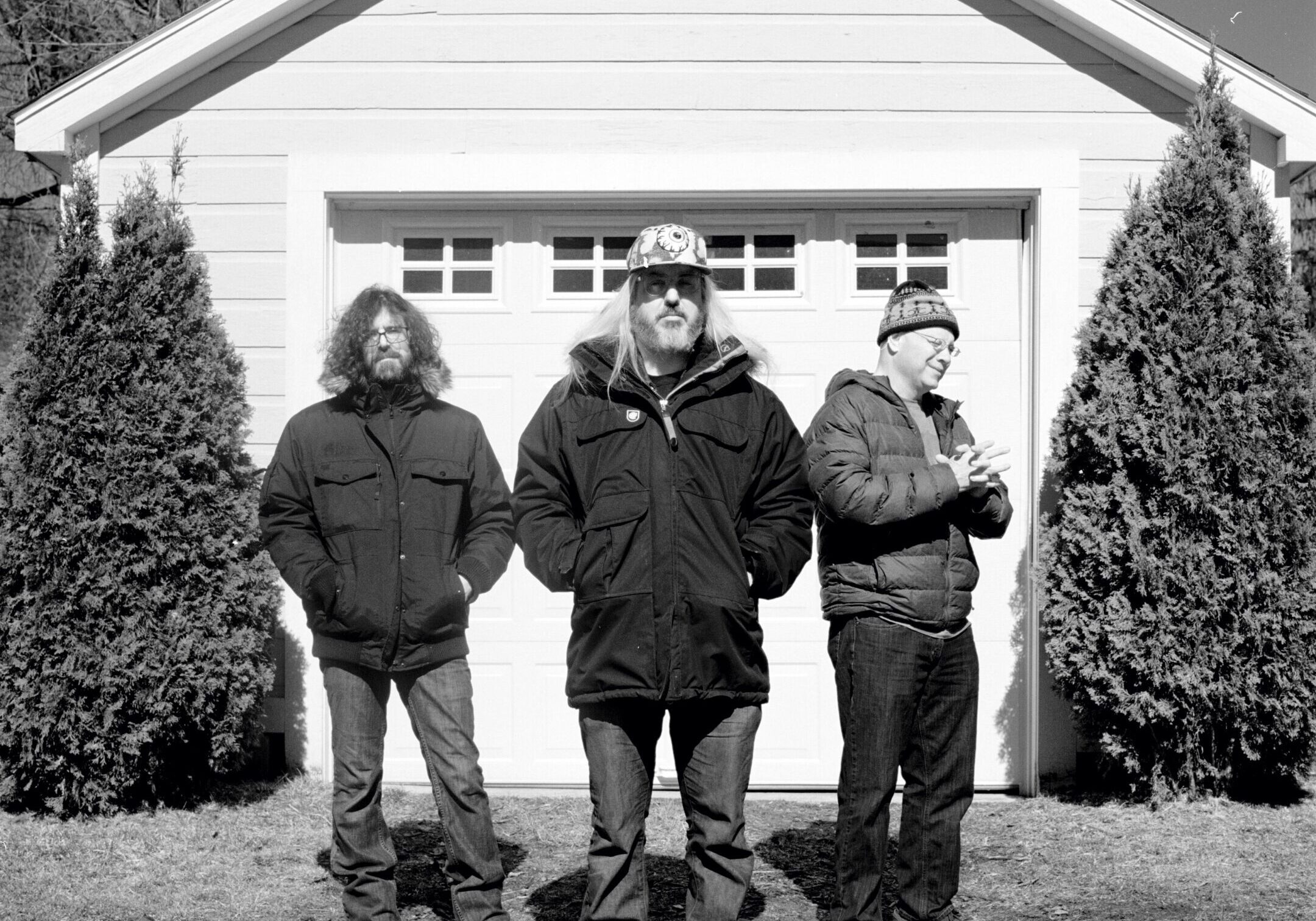 Three men standing in front of garage.