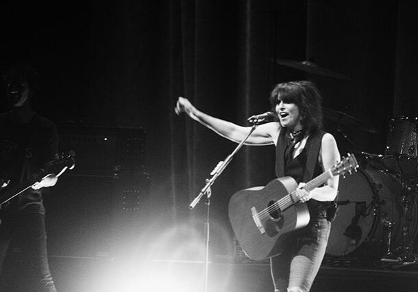 Singer performing on stage with guitar.