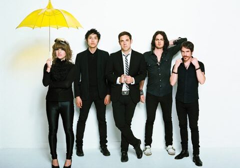 Five people posing with a yellow umbrella.
