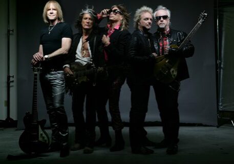 Five men with guitars in dark clothing.