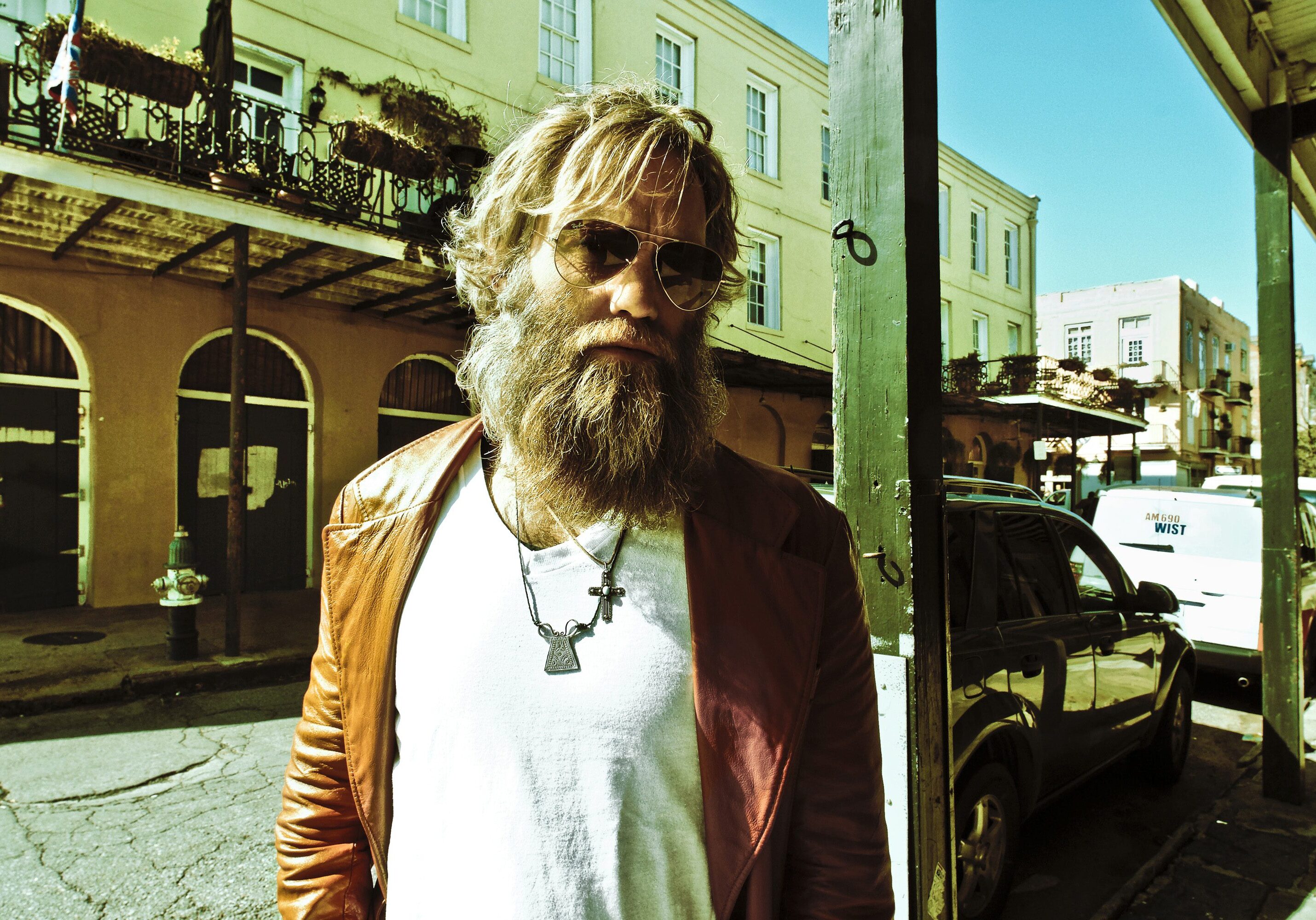 Man with sunglasses and beard on street.