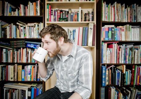 Man drinking coffee in a library.