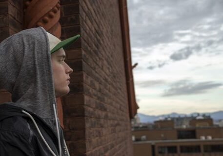 Person in hoodie looking at city skyline.