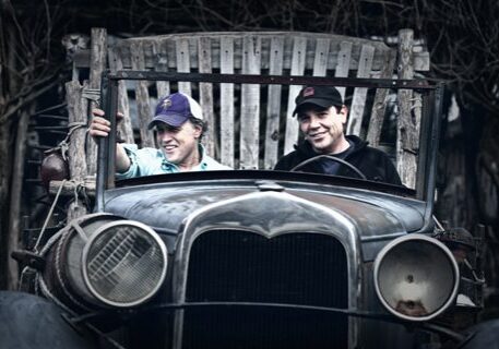 Two people sitting in vintage car.