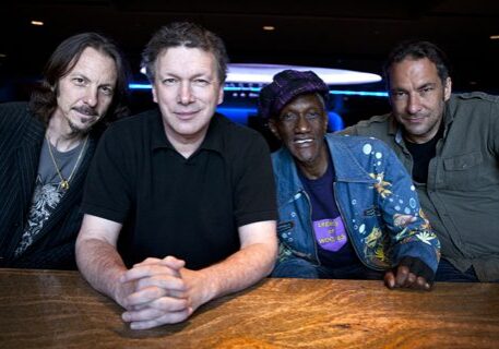 Four men sitting at a wooden table.