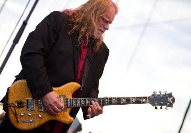 Guitarist performing on stage with electric guitar.