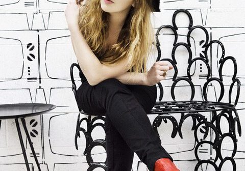 Woman in hat with red boots sitting.