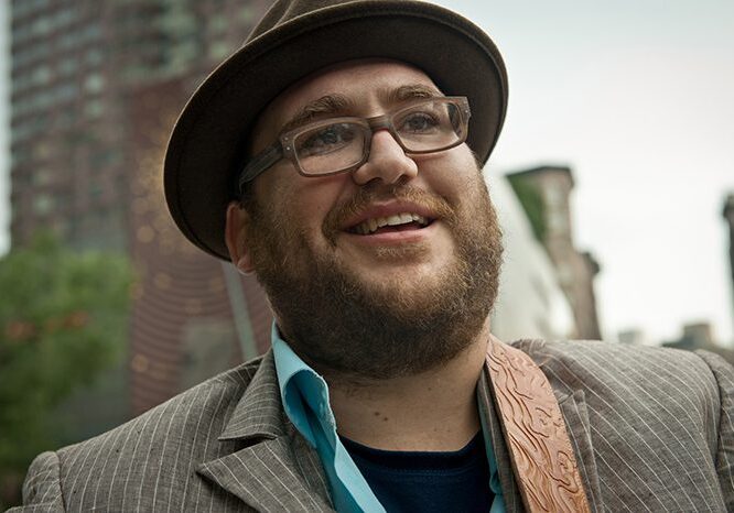 Man smiling in urban outdoor setting.