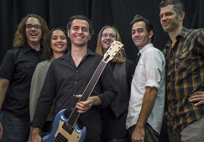 Band members smiling with electric guitar.