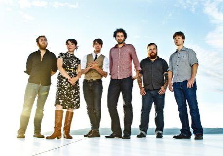Six people standing in a row outdoors.