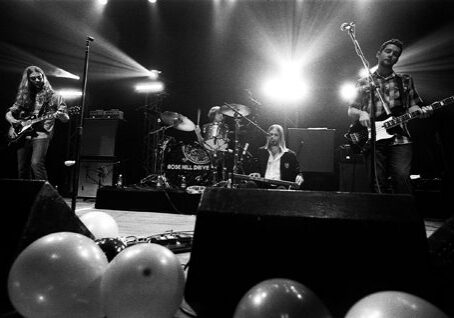Band performing on stage with balloons below.