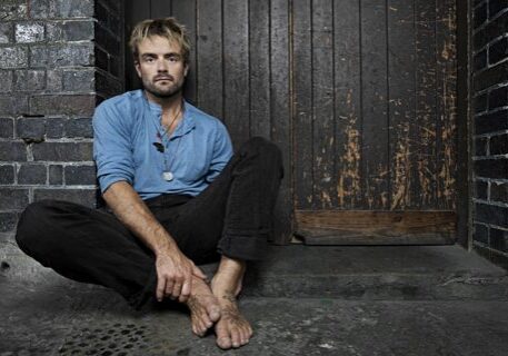 Man sitting against a wooden door.