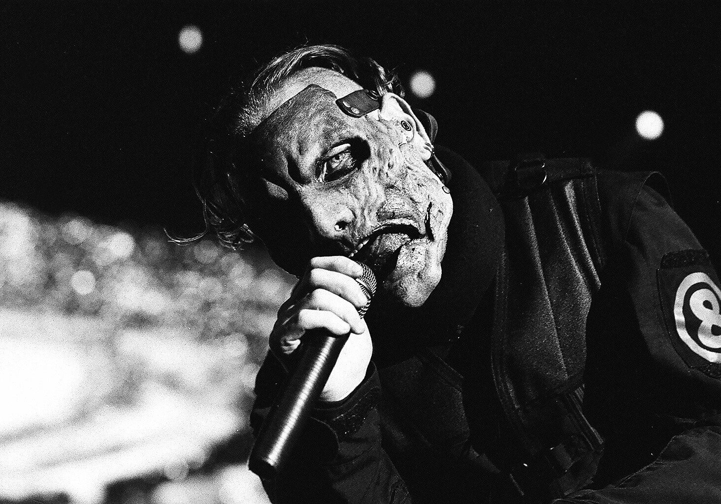 Masked performer singing passionately on stage.