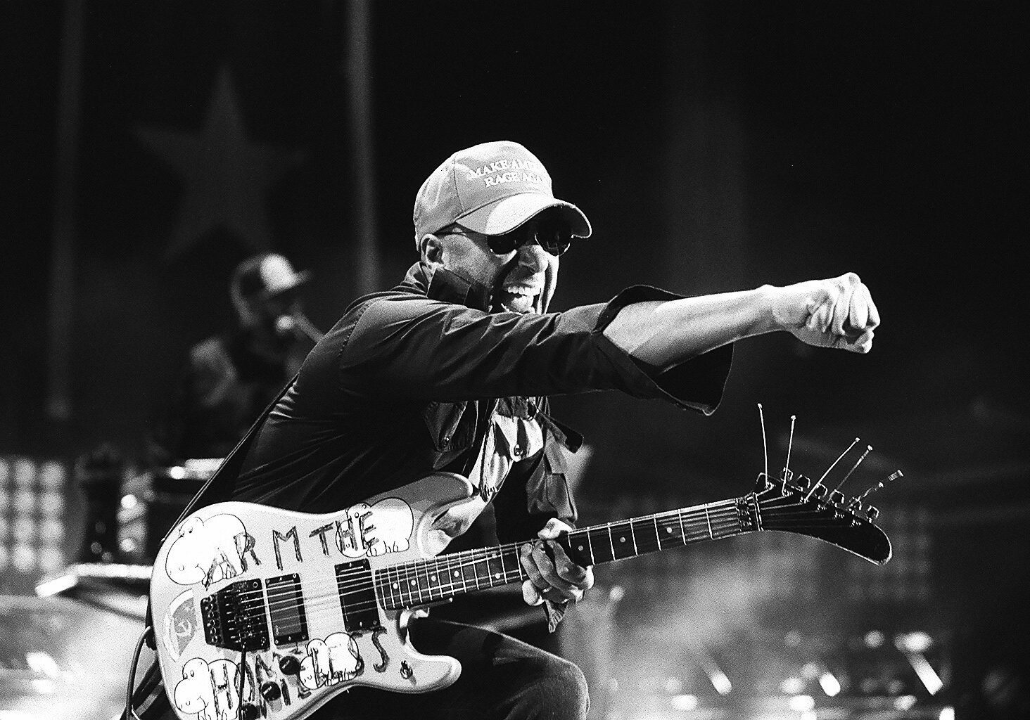 Guitarist performing energetically on stage, monochrome photo.