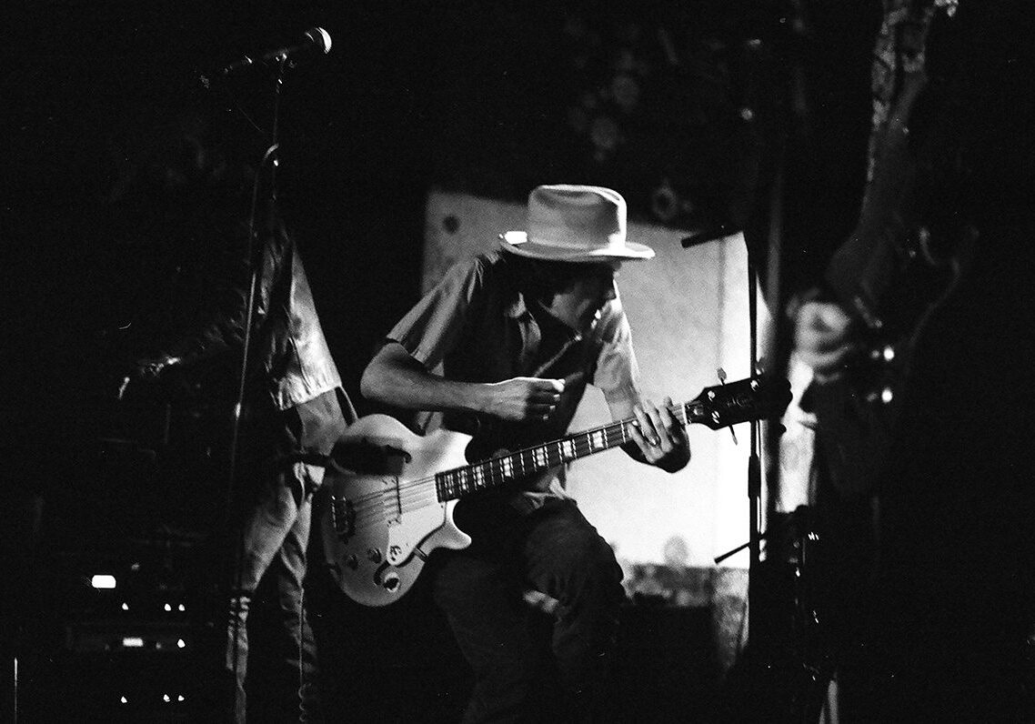 Musician playing guitar on dimly lit stage.