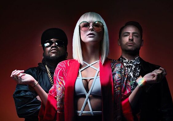 Three stylish people posing against dark background.