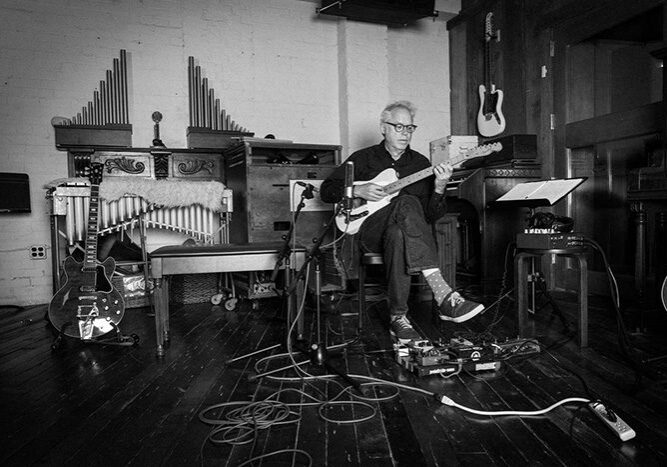 Musician playing guitar in a studio setting.