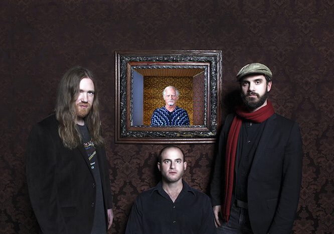 Four men posing, one in a picture frame.