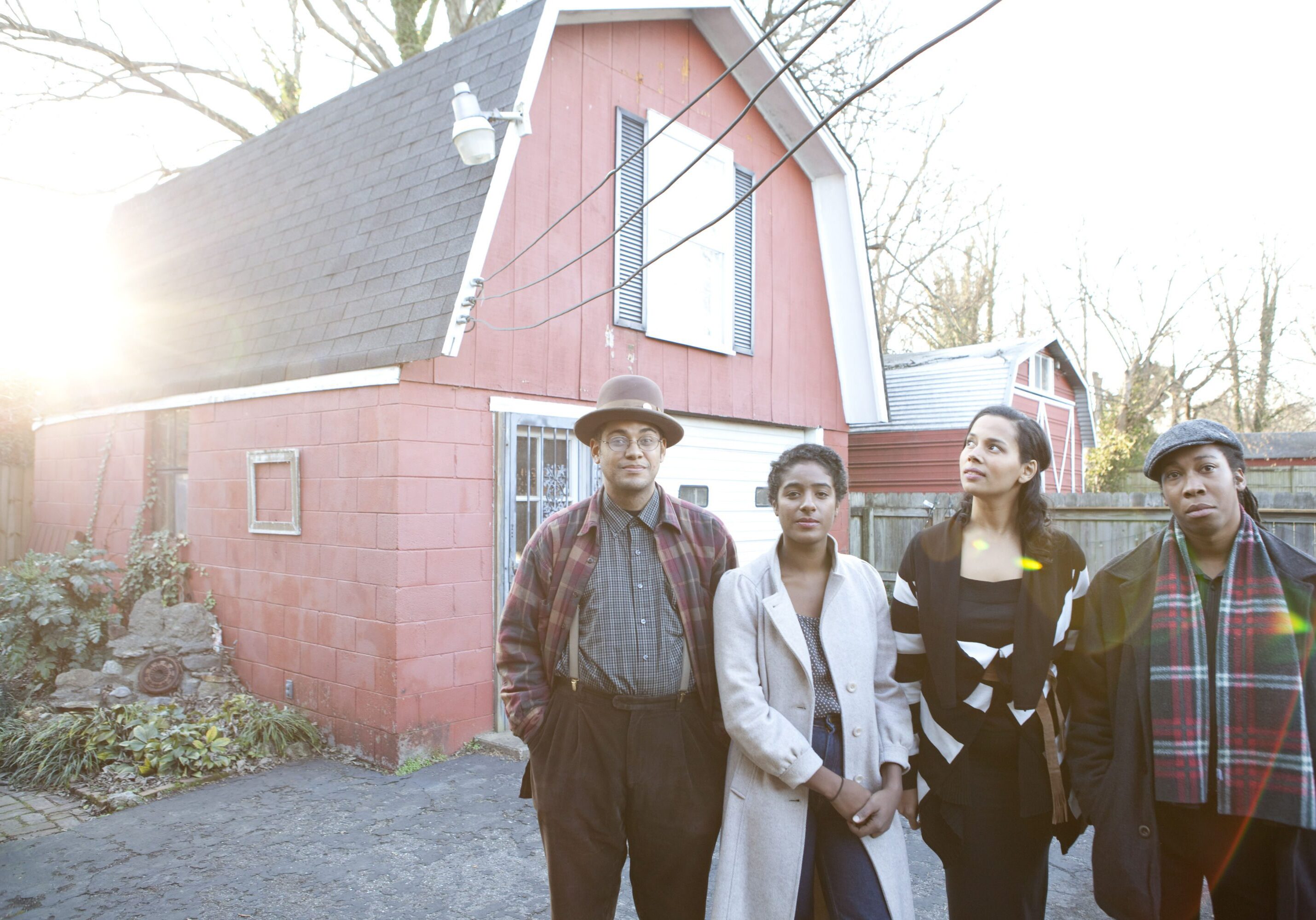 Four people standing outside red house.