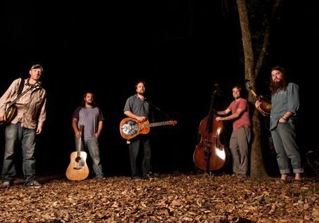 Band playing instruments in a forest setting.