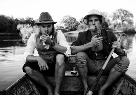 Two men smoking pipes in a boat.