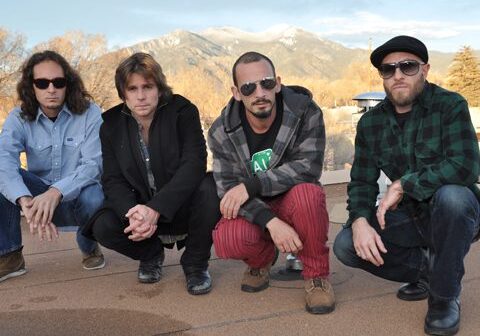 Four men posing outdoors with mountains behind.