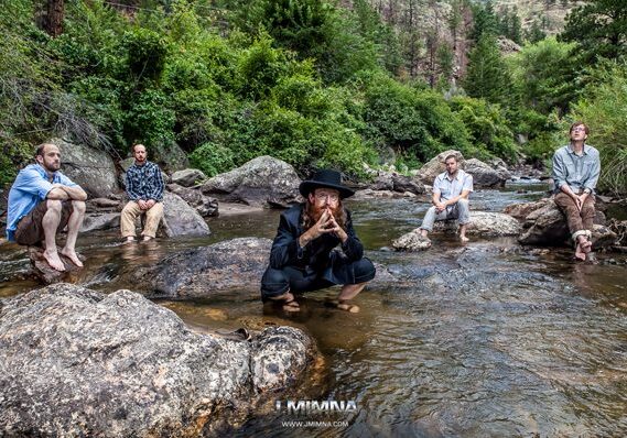 Group of people sitting on river rocks.