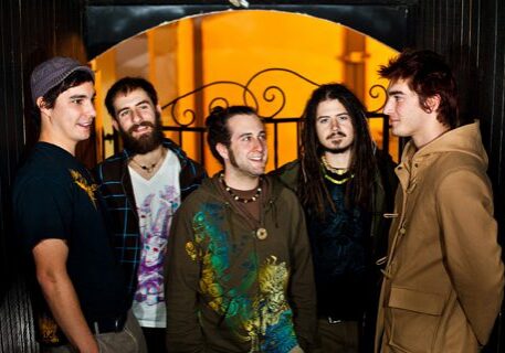 Group of five men standing together, smiling.